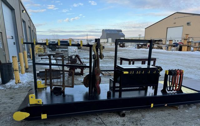 Completed black steel base beam with yellow lifting lugs; racks, toolboxes and storage hangers were added by the customer. Outdoors in winter