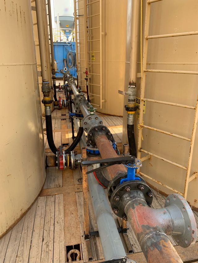 Pipe run between tanks, with a gate valve and a flanged tee in the foreground