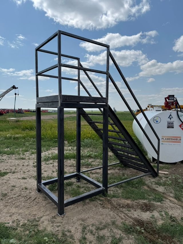 Black steel stair tower with a landing and handrails, set up outdoors
