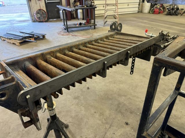 HWF storm bar laid down across a section of rust-colored rod fingers, on jack stands in the shop